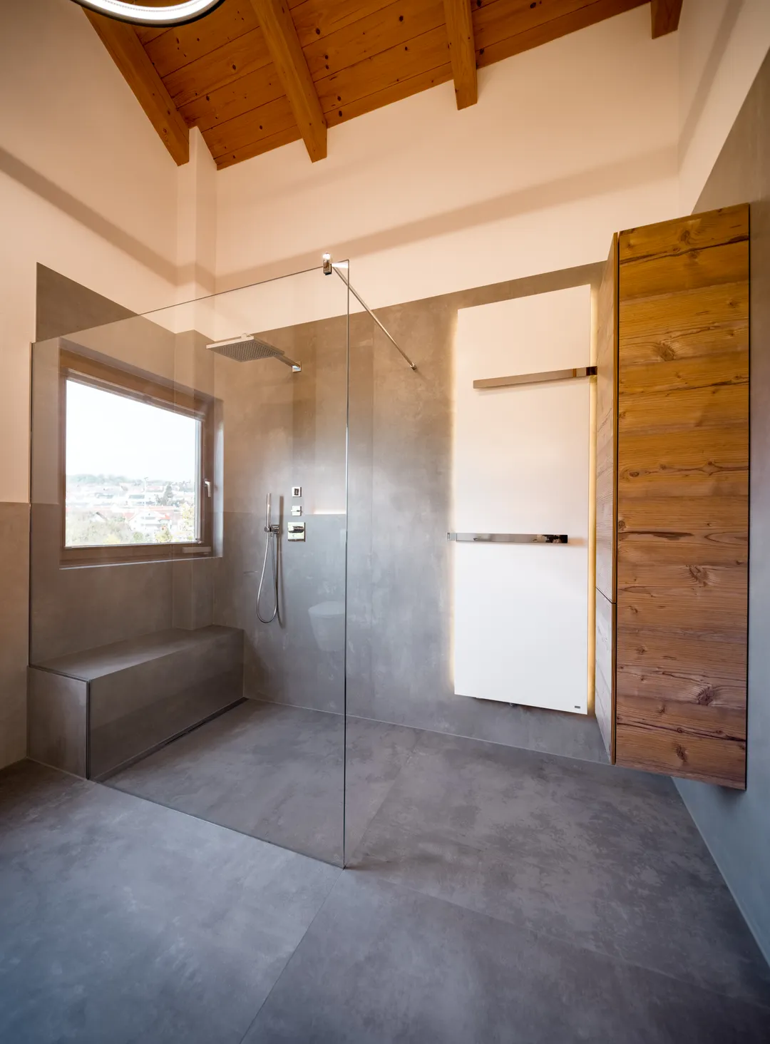 Dachbad mit Holzbalken: bodengleiche Dusche hinter Glas mit gefliester Sitzbank