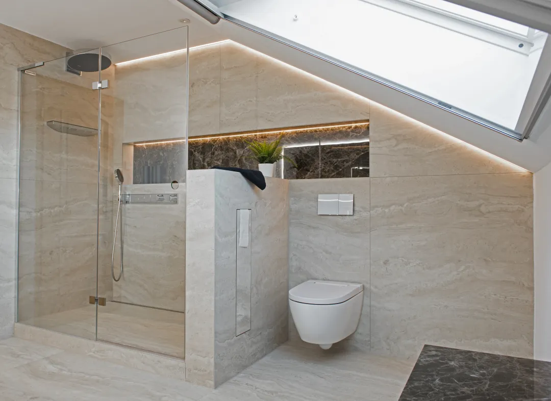 Bad in Travertin unter dem Dach: begehbare Dusche, Trennwand, WC und Dachfenster