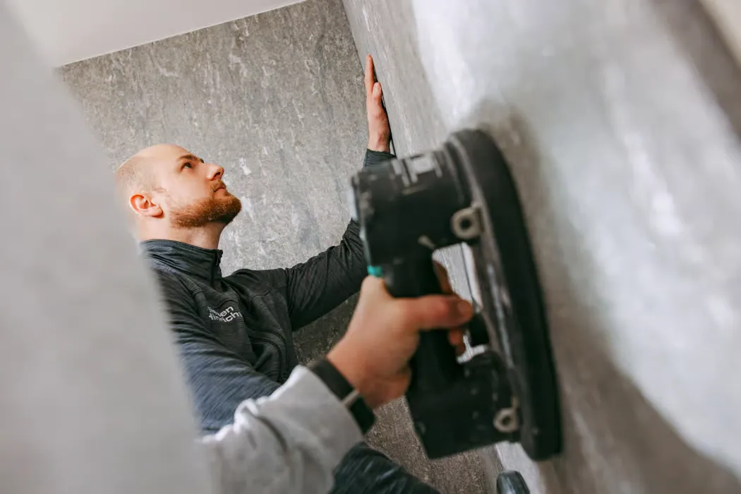 Stephan Hinrichs setzt eine Großformatplatte mit dem Saugheber an die Wand